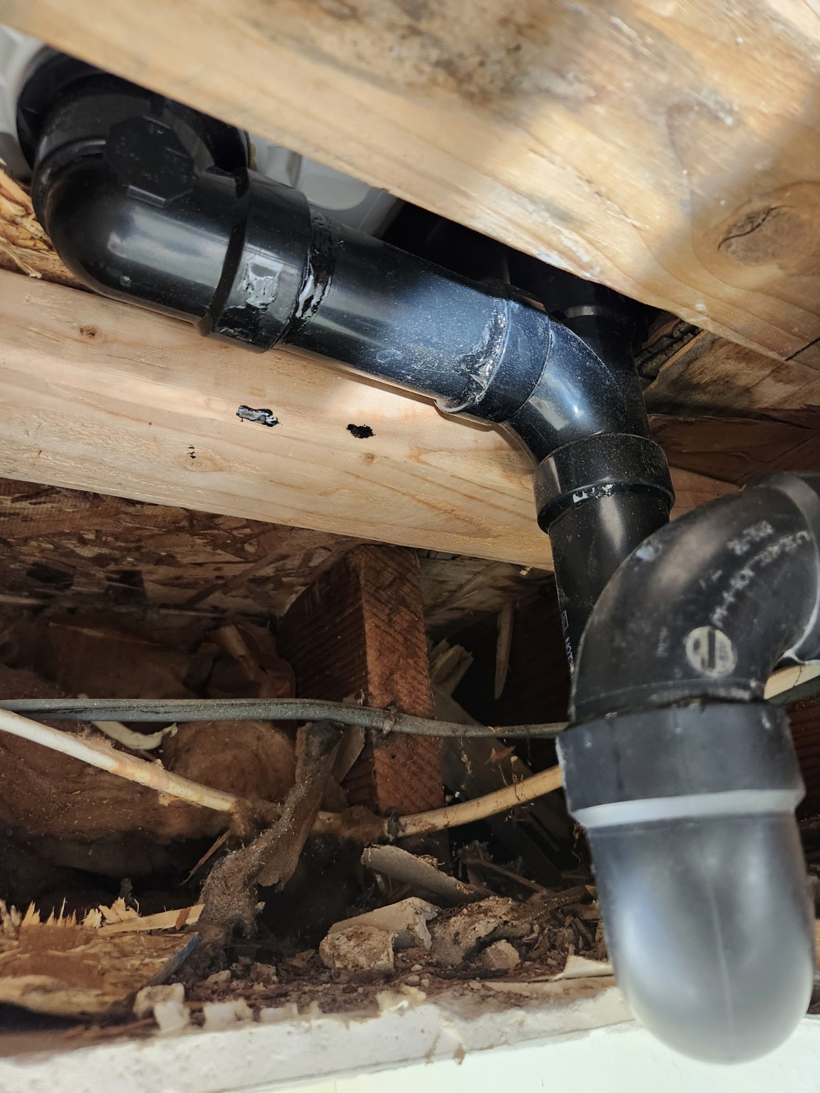 Completed black ABS drain piping repair beneath a floor